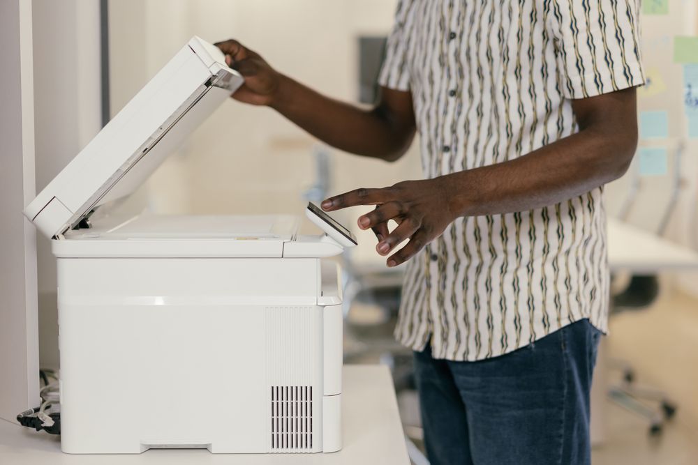 Hands lifting the lid of an office flatbed scanner